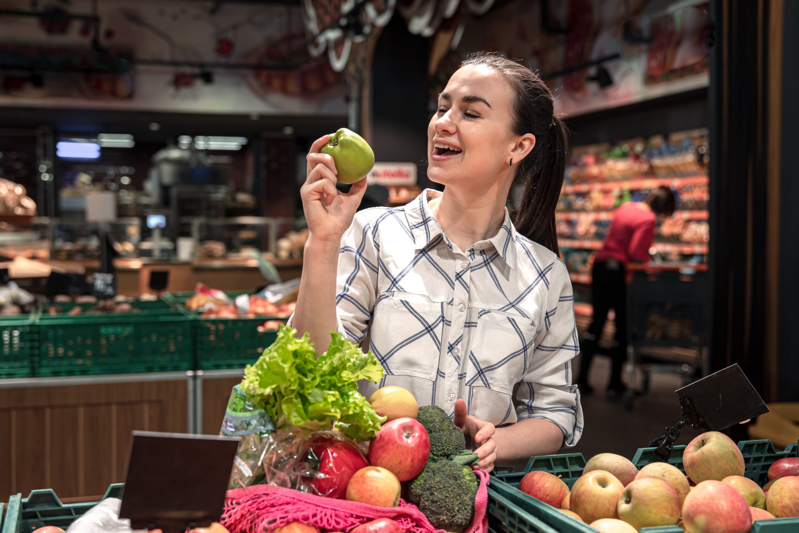 una joven elige frutas y verduras en un supermercado scaled